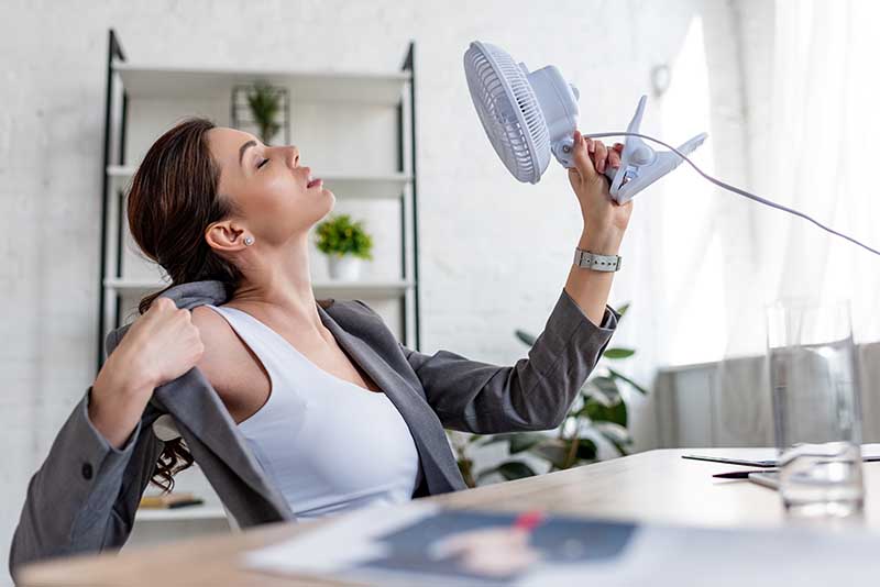 Woman with broken AC waiting for HVAC contractor to arrive.